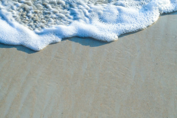 Beautiful soft wave and bubbles of sea water on the beach in sunny day of summer.
