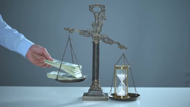 Sandglass outweighs dollars on scales, time is money, valuable resources usage