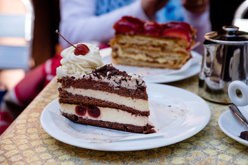 delicious looking french cherry cake with crean and cherry on top, on a white plate. Riquewihr, Alsace.
