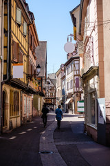 Gorgeous cobbled street in Colmar, Alsace, with people walking around during spring.