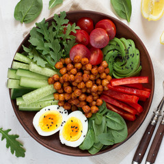 Buddha bowl, healthy and balanced food. Fried chickpeas, cherry tomatoes, cucumbers, paprika, eggs, spinach, arugula