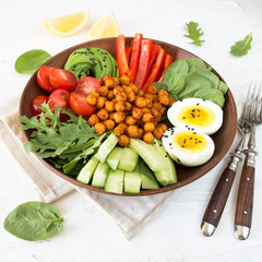 Buddha bowl, healthy and balanced food. Fried chickpeas, cherry tomatoes, cucumbers, paprika, eggs, spinach, arugula