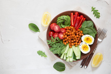 Buddha bowl, healthy and balanced food. Fried chickpeas, cherry tomatoes, cucumbers, paprika, eggs, spinach, arugula