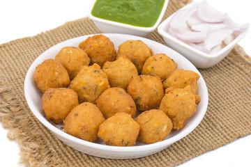 Indian Spicy Street Food Dal Vada Also Know as Moong Dal Vada, Pakoda, Pakode, Pakore, Moong Vada, Pakora or Bhajiya Served with Green Chutney or Onion isolated on White Background