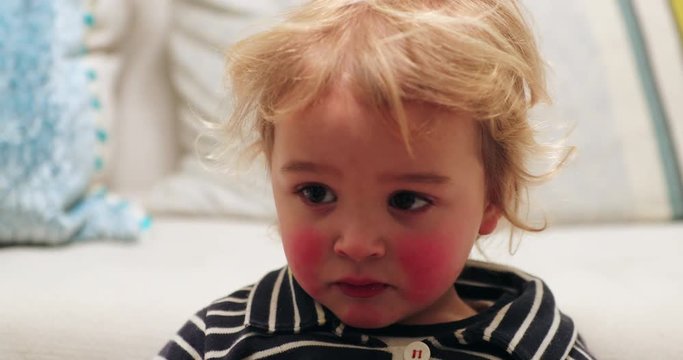 Closeup of blonde child baby infant toddler with red cheaks starring off camera