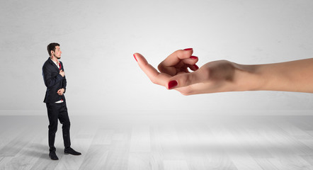 Businessman with kisses on his face in an empty space where a big hand baiting him
