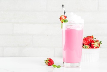 Cold strawberry  milkshake with fresh berries and mint on white marble background copy space