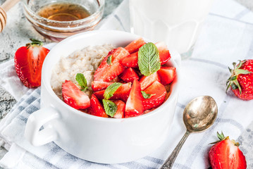 Healthy summer breakfast, overnight oatmeal with fresh strawberry and milk, grey stone background
