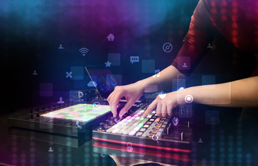 Hand mixing music on dj controller with social media concept icons
