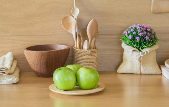 Green Apples And Wooden Plates In The Kitchen.