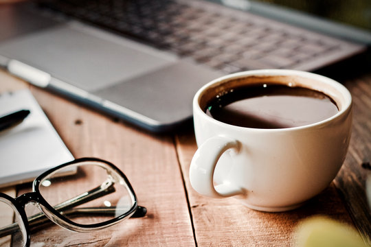 Desk work coffee cup and laptop notebook pen on wooden table