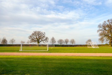 Fototapeta na wymiar Empty football goalposts in playing fields on a summer morning,