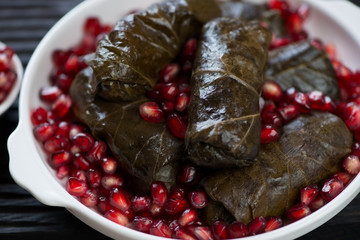Eastern cuisine dolma or stuffed grape leaves served with pomegranate seeds, selective focus, closeup