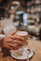 Girl holding a cup of hot coffee in café
