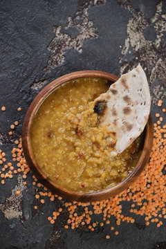 Top view of thick red lentil soup or indian masoor dahl served with chapati in a wooden bowl, studio shot