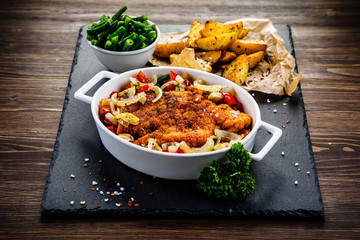 Fried pork chop with vegetables on wooden background 