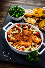 Fried pork chop with vegetables on wooden background 
