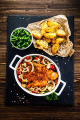 Fried pork chop with vegetables on wooden background 