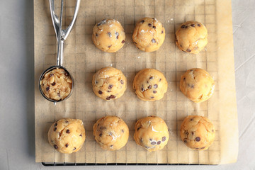 Raw cookie dough with chocolate chips and scoop on parchment paper, top view
