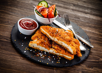 Fried pork chop with vegetables on wooden background