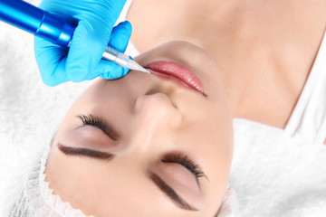 Young woman getting permanent makeup on lips in beautician salon, closeup