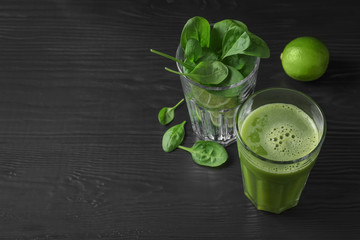 Glasses with delicious detox juice and ingredients on dark background