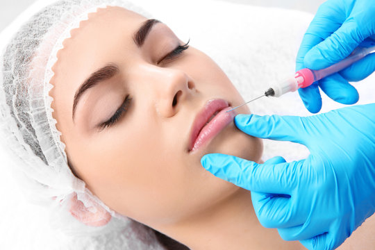Young woman getting lip injection in beautician salon