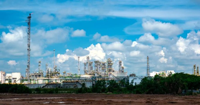 Oil refinery plant behide row of tree and blue sky with cloud, Thailand