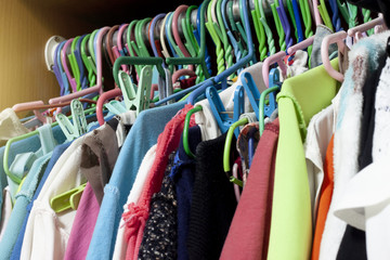 Clothes hanging in a variety of colors are not grouped.