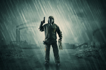 Gas masked survival man coming with arms on his hand  in a demolished dark environment 
