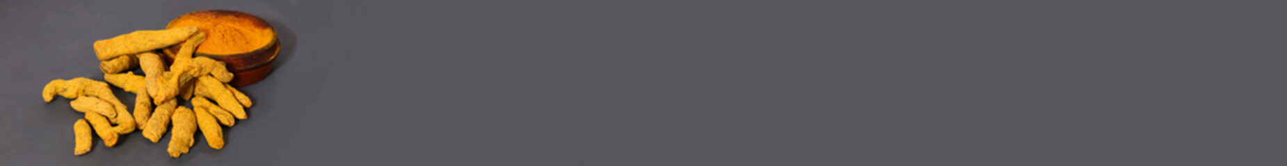 Banner width powder turmeric and whole dry root on grey. Space for your text