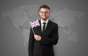 Cheerful businessman standing in front of a map with flag on his hand
