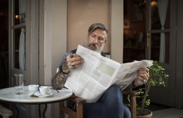 Porträt eines bärtigen Mannes im Cafe Zeitung lesend