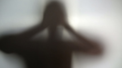 Silhouette of person holding head in hands, suffering from terrible headache