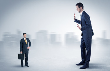 Obraz premium Giant businessman being afraid of small serious executor with suitcase 