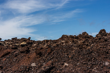 Volcanic crater in the Timanfaya National Park under a blue sky with clouds. Lanzarote, Canary Islands, Spain.