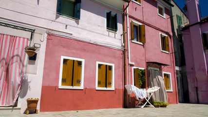 Old colored residential houses on Burano island, hot summer day in Italy, Venice