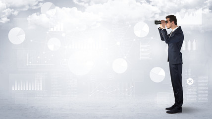 Businessman looking forward with binoculars cloudy background and graphs, charts around
