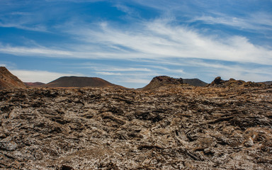 Volcanic crater in the Timanfaya National Park under a blue sky with clouds. Lanzarote, Canary Islands, Spain.