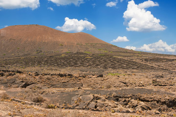 Volcanic crater in the Timanfaya National Park under a blue sky with clouds. Lanzarote, Canary Islands, Spain.