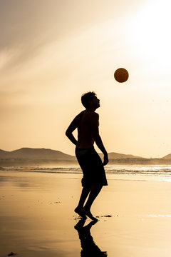 Silhouette of a man playing football (soccer) at sunset. Famara beach, Lanzarote, Canary Islands, Spain.