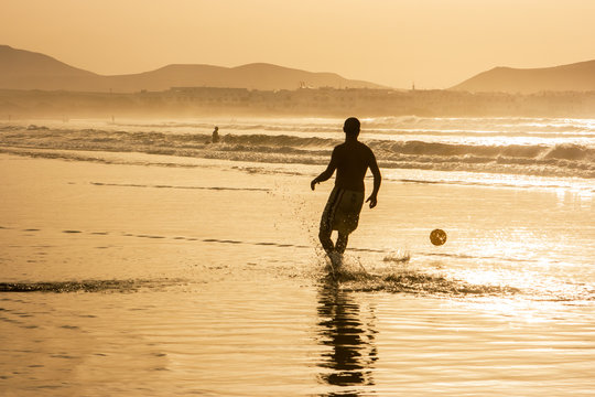 Silhouette of a man playing football (soccer) at sunset. Famara beach, Lanzarote, Canary Islands, Spain.
