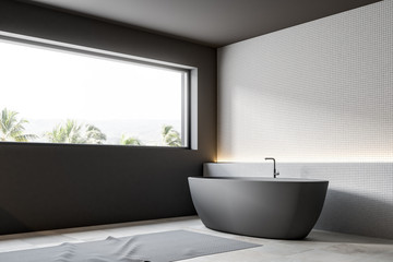 Fototapeta na wymiar Gray boat shaped bathtub, white tiles, side view