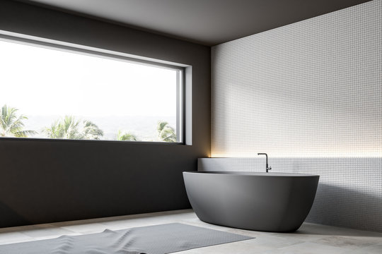 Gray boat shaped bathtub, white tiles, side view