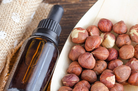 Organic  Hazelnut Oil  And  Whole Hazelnuts  On Wooden Table. Organic And Natural Skin Care Concept.