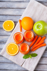 Jars with carrot juice, apple, sliced orange and mint leaf 