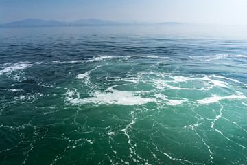 Naklejka na ściany i meble Turquoise blue wavy seawater with foam and waves, background texture.