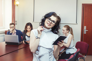 Happy successful businesswoman in the office with colleagues in the background.