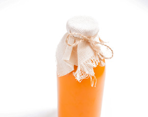 Glass transparent bottle with orange juice on a light background