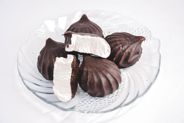 a few marshmallows in chocolate on a transparent dish on a light background